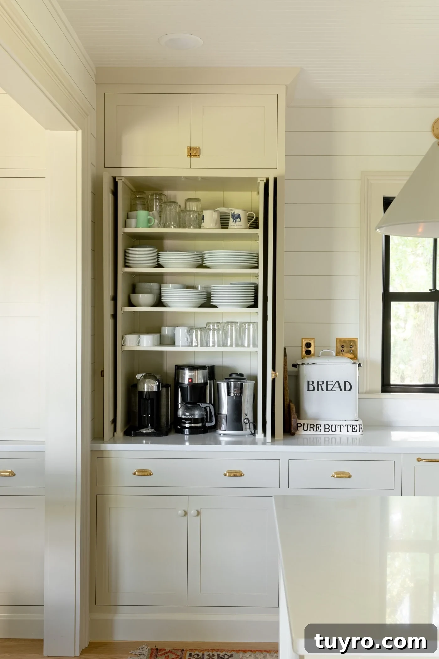Large upper cabinet sitting on countertop with doors open revealing plates, mugs, bowls, and coffee maker