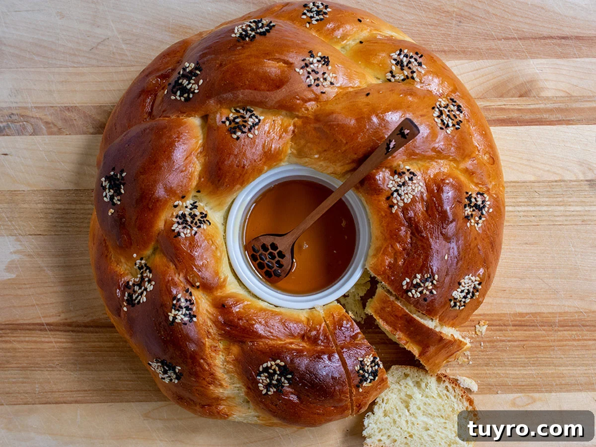 How to Braid Challah: Step-by-Step Visual Guide 6 Round challah with a white ramekin in the center filled with honey and one slice cut out of the bread.