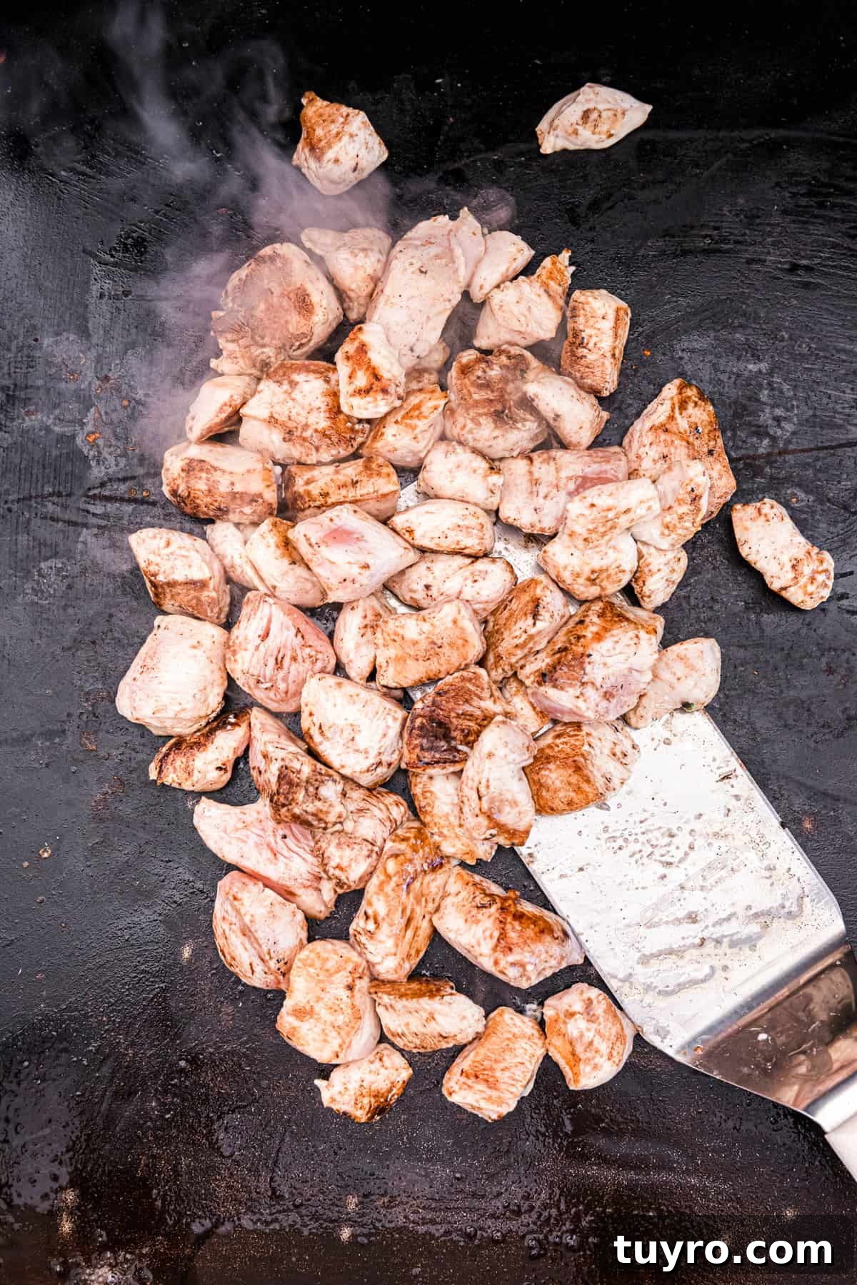 Blackstone Teriyaki Chicken Recipe: Sticky Glazed Griddle Chicken 6 Coating the chicken cubes with teriyaki sauce on Blackstone for Teriyaki Chicken