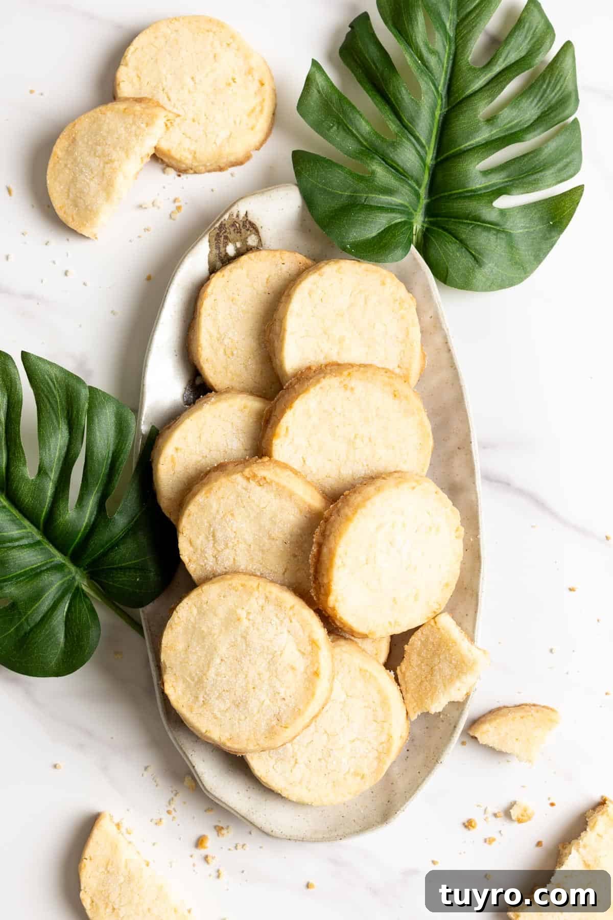A stack of coconut shortbread cookies with a half eaten one on top