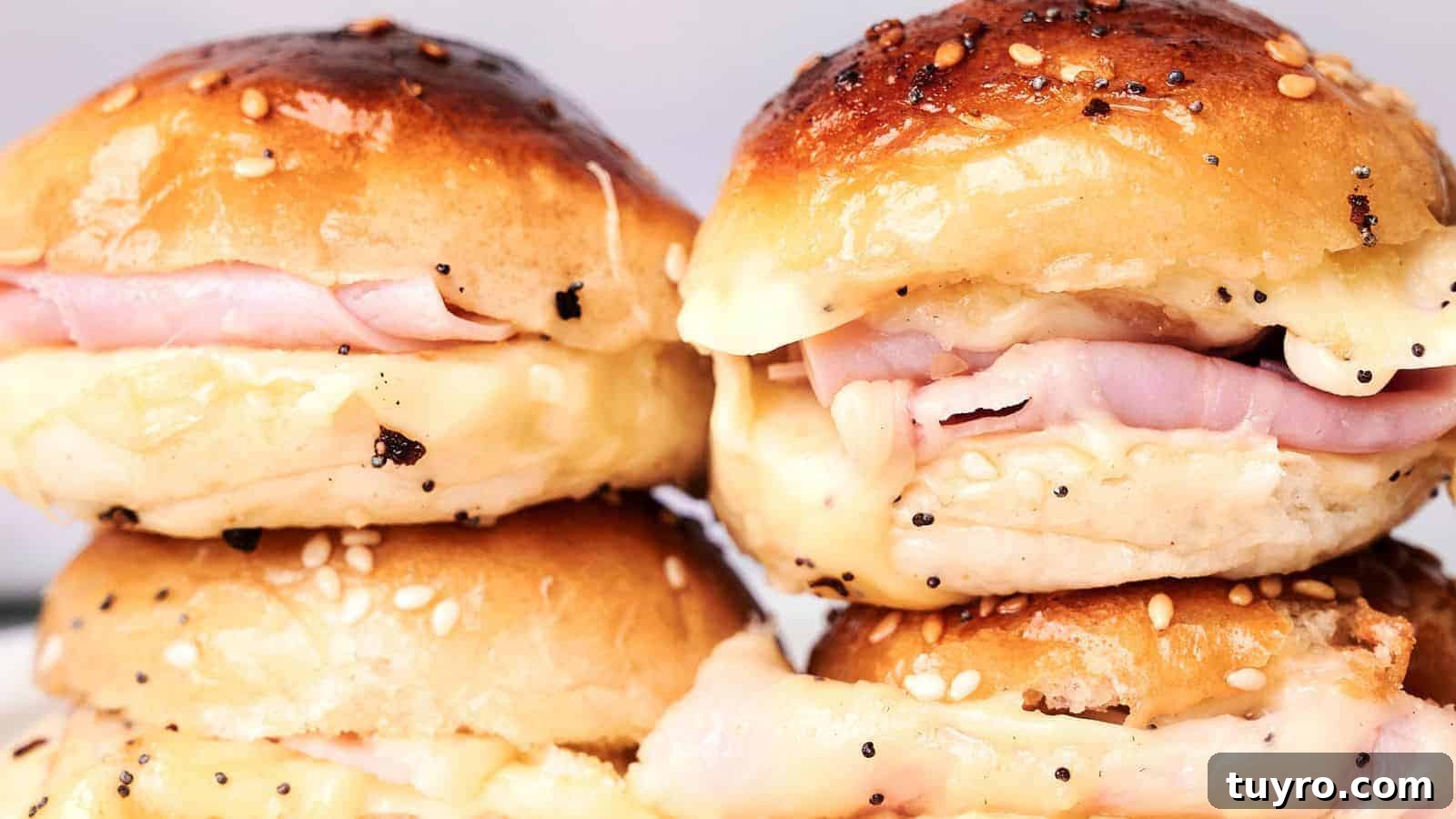 9 Ham Recipes Everyone Will Request Next Year 4 Close-up of four ham and cheese sliders on sesame seed buns, arranged in two stacks. The cheese is melting and oozing out of the sides, making these Ham and Cheese Sliders irresistible.