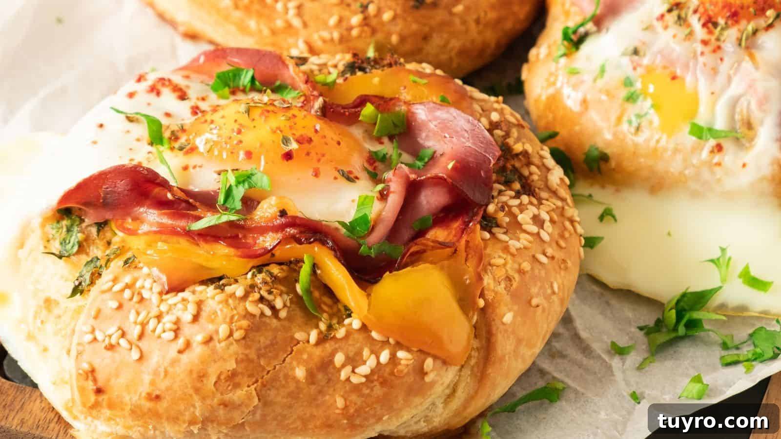 9 Ham Recipes Everyone Will Request Next Year 6 Close-up of a savory pastry topped with a sunny-side-up egg, sliced ham, yellow bell pepper, and garnished with chopped parsley, served on a sesame seed bun.