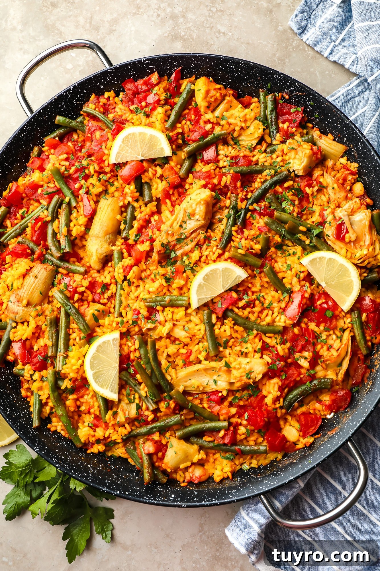 Vegan Paella with Saffron and Roasted Vegetables 5 vegan paella topped with lemon slices in a large black paella pan.