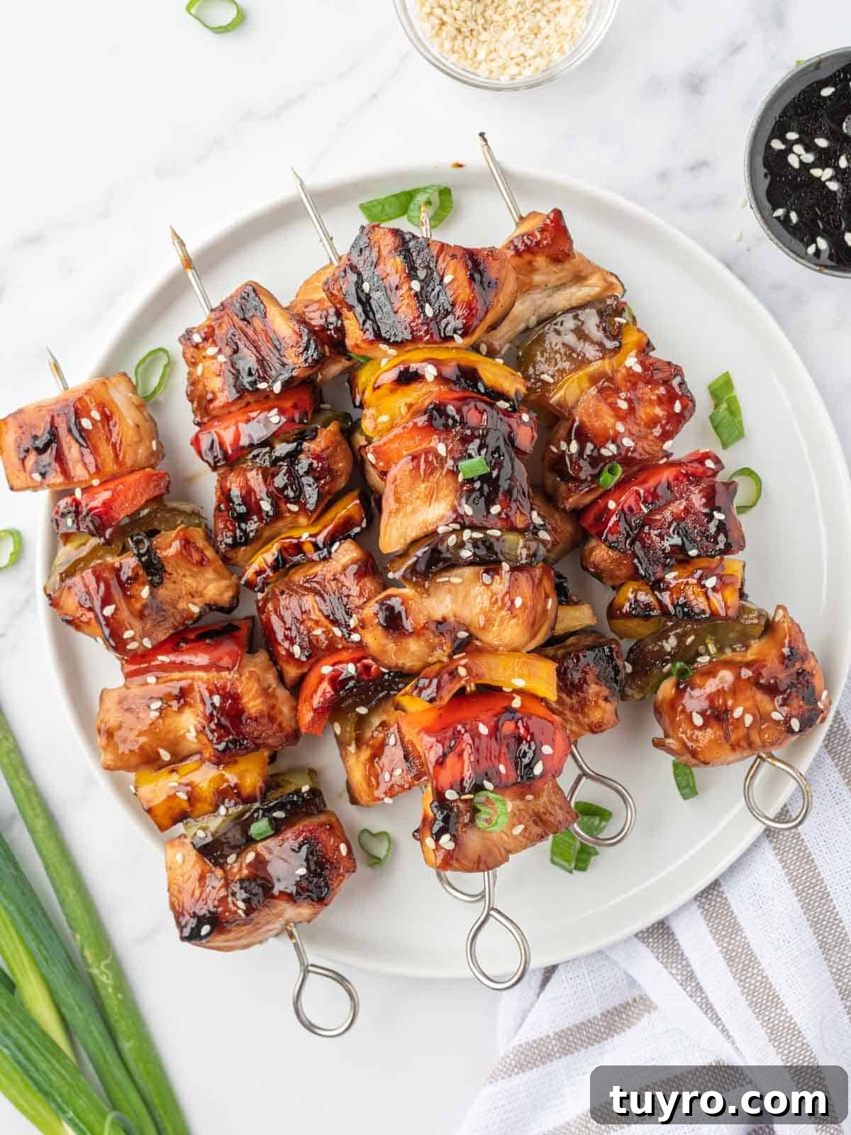 A pile of grilled chicken teriyaki skewers on a round platter.