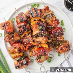 A pile of grilled chicken teriyaki skewers on a round platter.