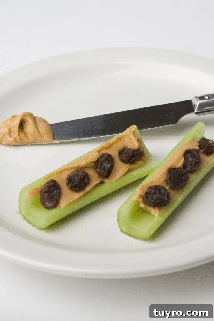Celery with peanut butter and raisins with a knife on a plate