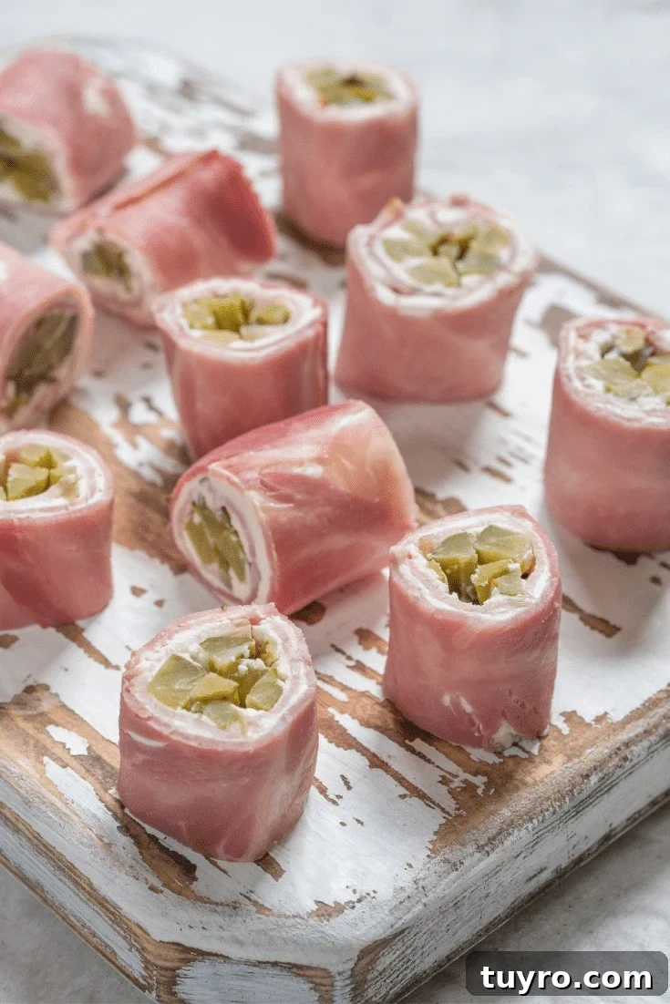 Pickles wrapped in ham with a layer of cream cheese on a serving board