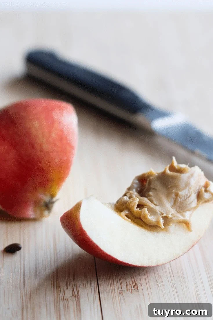 An apple slice with almond butter and a knife