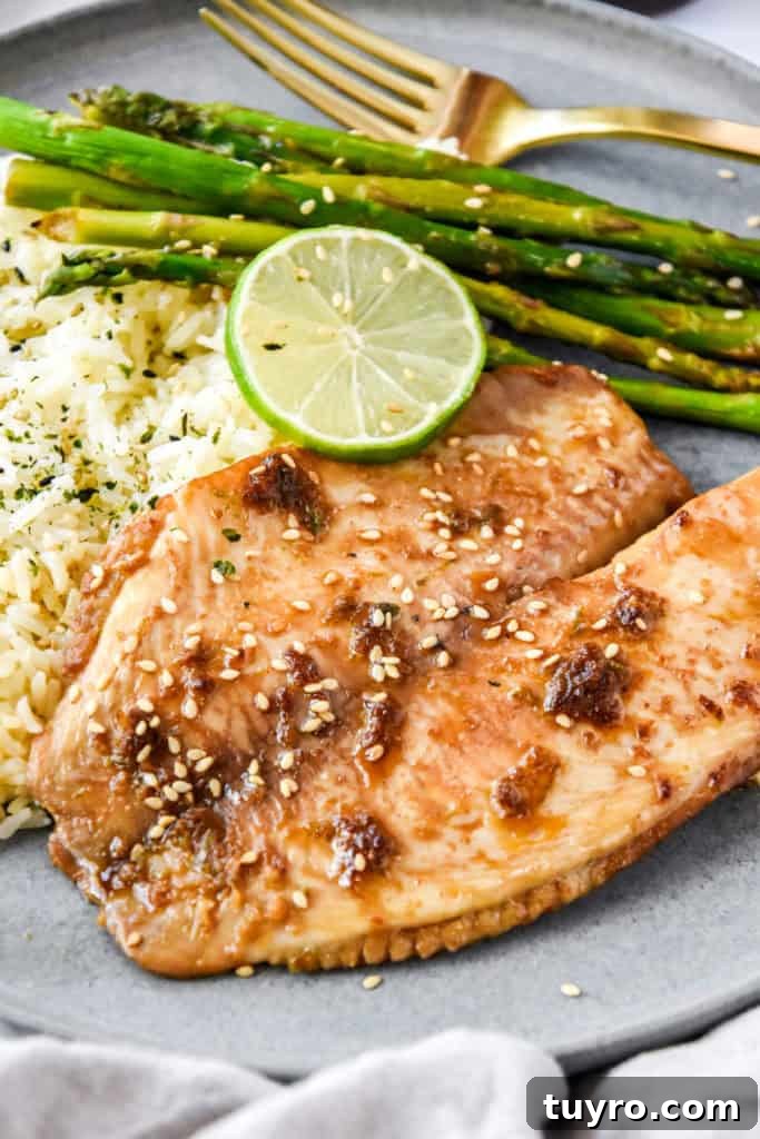Ginger-Soy Tilapia with Broiled Asparagus Recipe 12 baked tilapia on a plate with rice and asparagus.