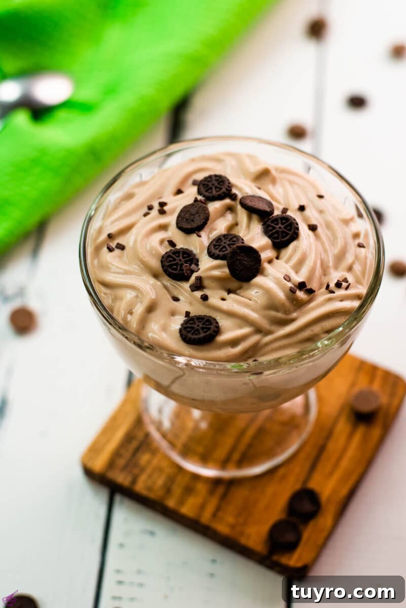5 Ingredient Chocolate Cornstarch Pudding Recipe 2 Beautifully textured chocolate cornstarch pudding in a dessert glass. Placed on a wooden coaster on a white wooden floor. Decorated with small pieces of biscuit.