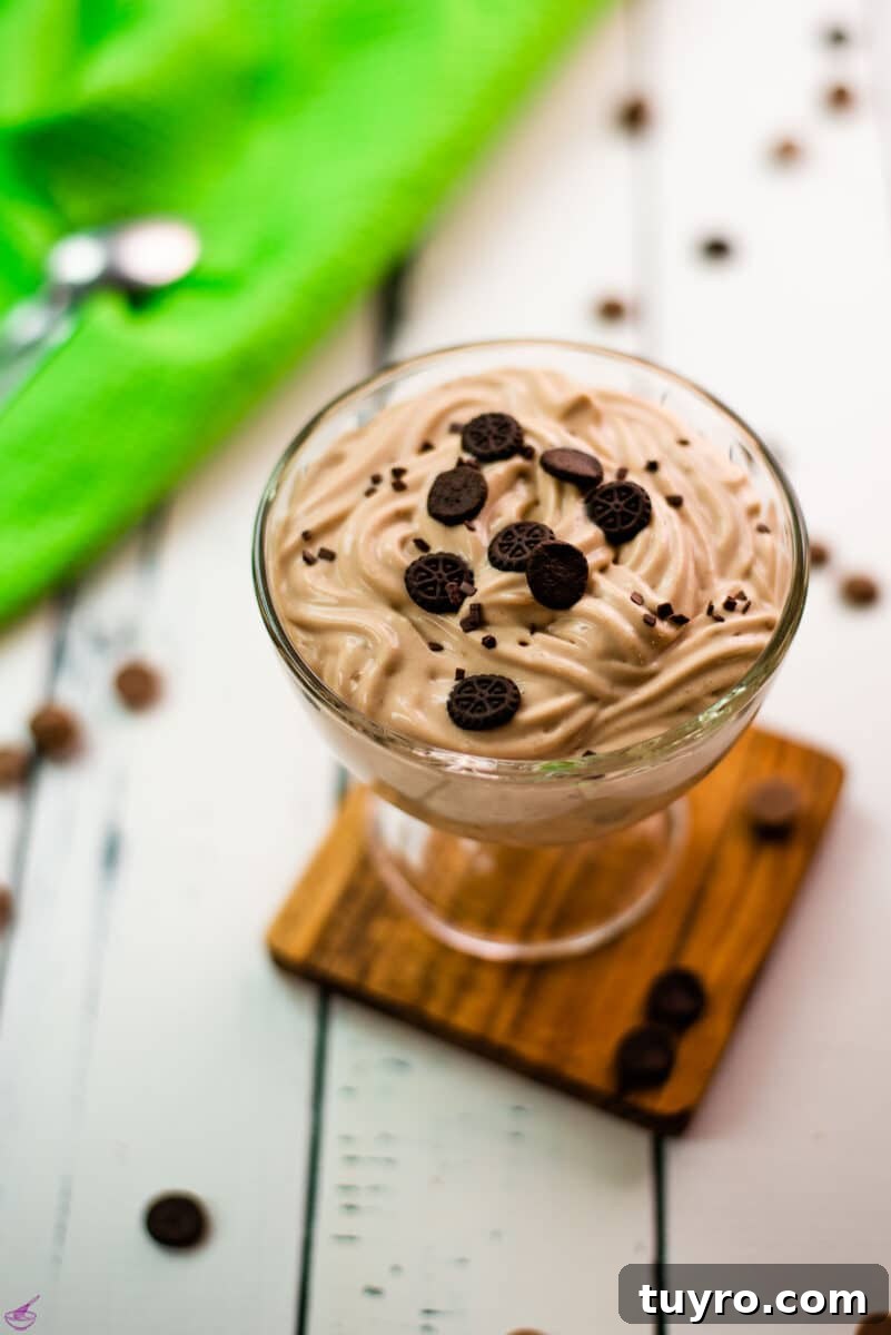 5 Ingredient Chocolate Cornstarch Pudding Recipe 6 Beautifully textured chocolate cornstarch pudding in a dessert glass. Placed on a wooden coaster on a white wooden floor. Decorated with small pieces of biscuit.