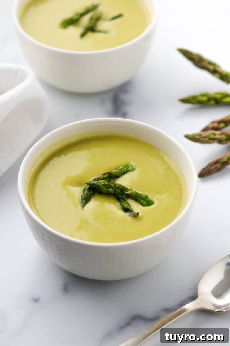 Creamy Asparagus Soup with Leeks and Peas 10 A bowl of Creamy Asparagus, Leek and Pea Soup next to a spoon.