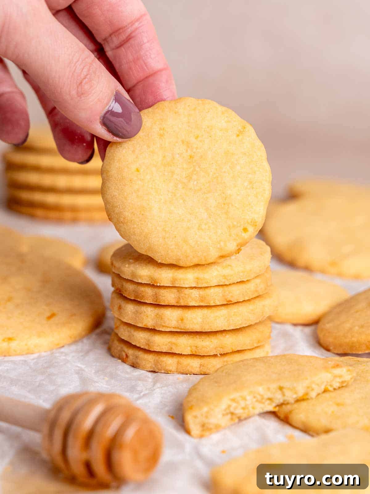 Honey Orange Shortbread Cookies — No-Chill Cut-Out Recipe 2 Grabbing an orange shortbread cookie from a stack of them.