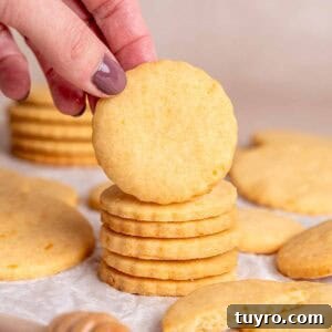 Honey Orange Shortbread Cookies — No-Chill Cut-Out Recipe 16 A hand grabbing an orange shortbread cookie from a stack.