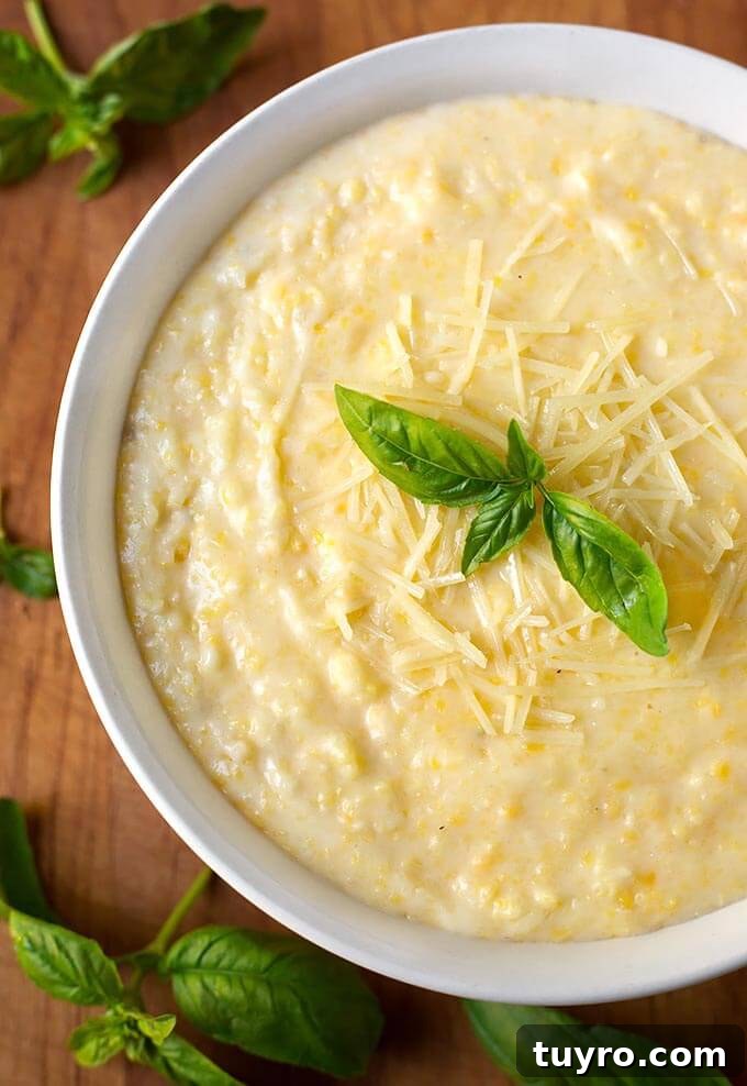 Creamy Instant Pot Polenta Recipe 2 Polenta in a white bowl on a wooden board garnished with basil