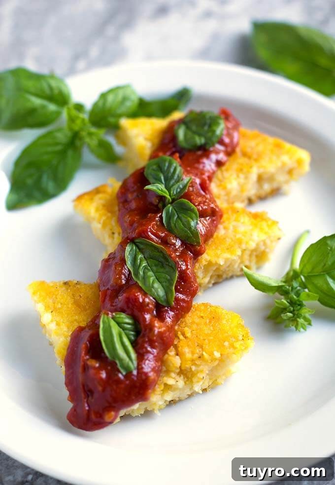 Creamy Instant Pot Polenta Recipe 3 Polenta slices on a white plate with red sauce and basil leaves