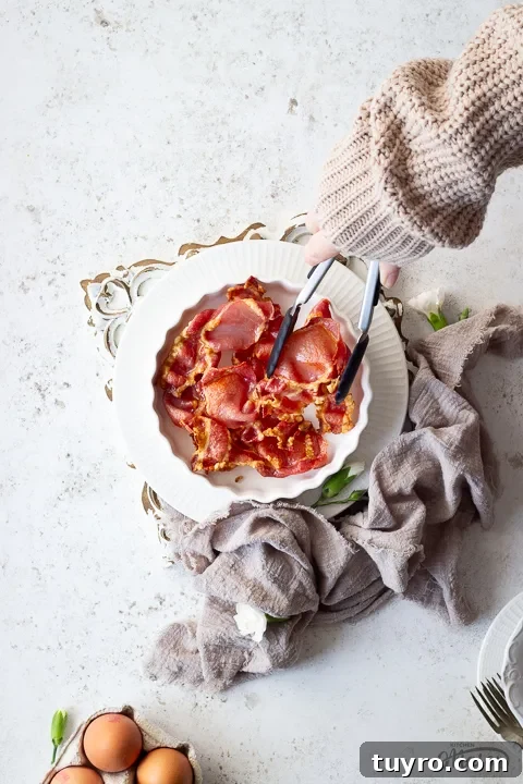 Crispy 10-Minute Air Fryer Bacon Recipe (UK) 6 Air fried bacon being taken out of a white dish
