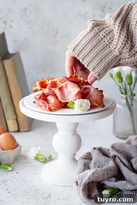 Crispy 10-Minute Air Fryer Bacon Recipe (UK) 2 Someone picking up a piece of air fried bacon from a plate on a stand