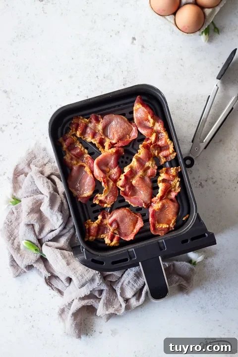 Crispy 10-Minute Air Fryer Bacon Recipe (UK) 14 Cooked back bacon in an air fryer drawer with tongs