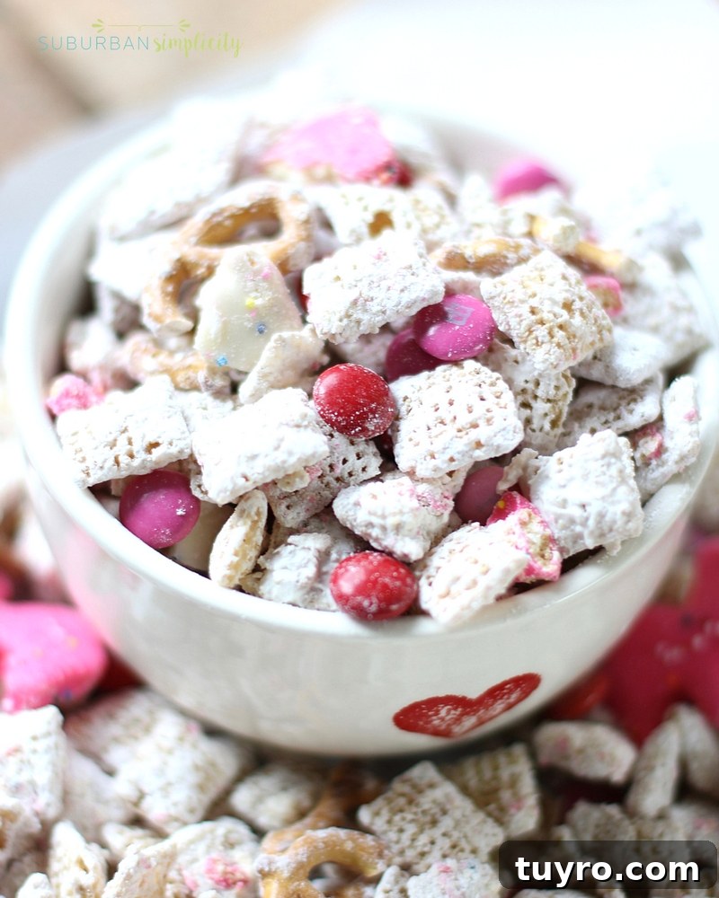 Valentines Day Puppy Chow Recipe 2 Valentine's Day Puppy Chow made from chex cereal in a bowl with a heart on it.