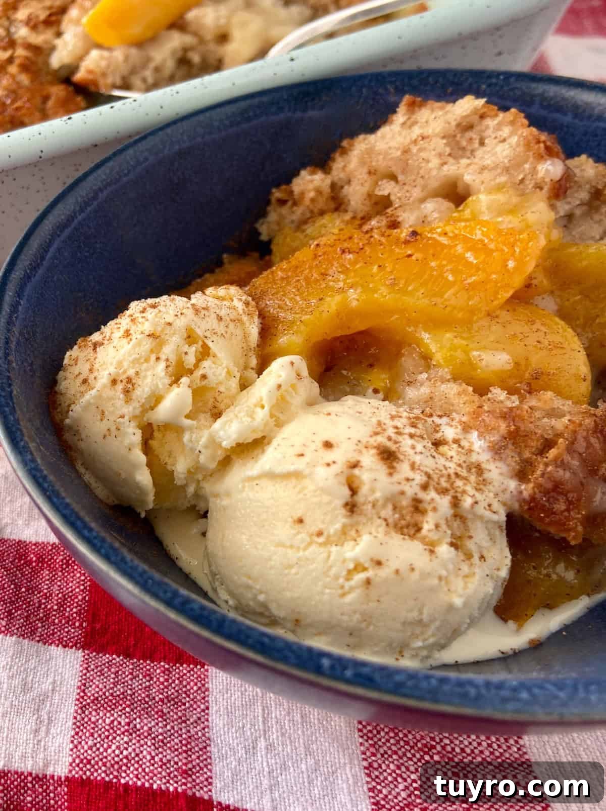 Classic Southern Peach Cobbler Recipe – Authentic & Irresistible 5 Peach cobbler with vanilla ice cream in blue bowl.