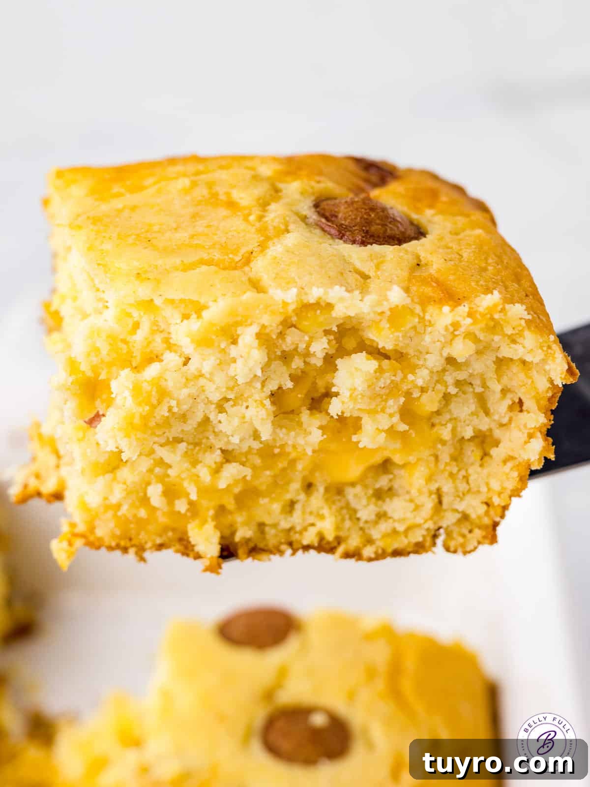 Corn Dog Casserole with Cornbread and Hot Dogs 4 square piece of cornbread with hot dogs on serving spatula