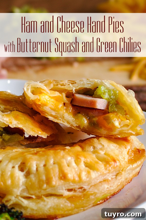 Two ham and cheese hand pies on a plate, one broken open to see the filling.