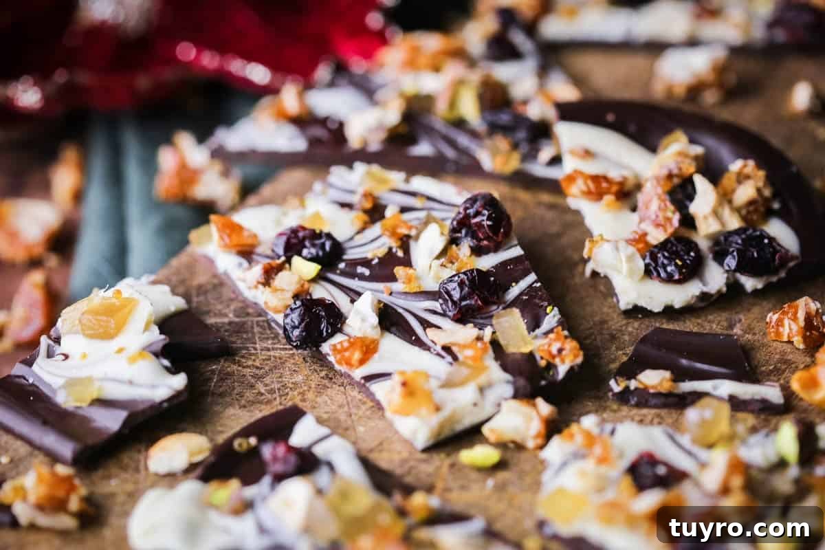 Christmas Chocolate Bark Recipe with Festive Toppings 12 Christmas Chocolate Bark snapped into shards on a wooden board.
