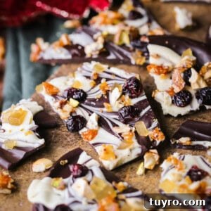 Christmas Chocolate Bark Recipe with Festive Toppings 14 Christmas Chocolate Bark snapped into shards on a wooden board.