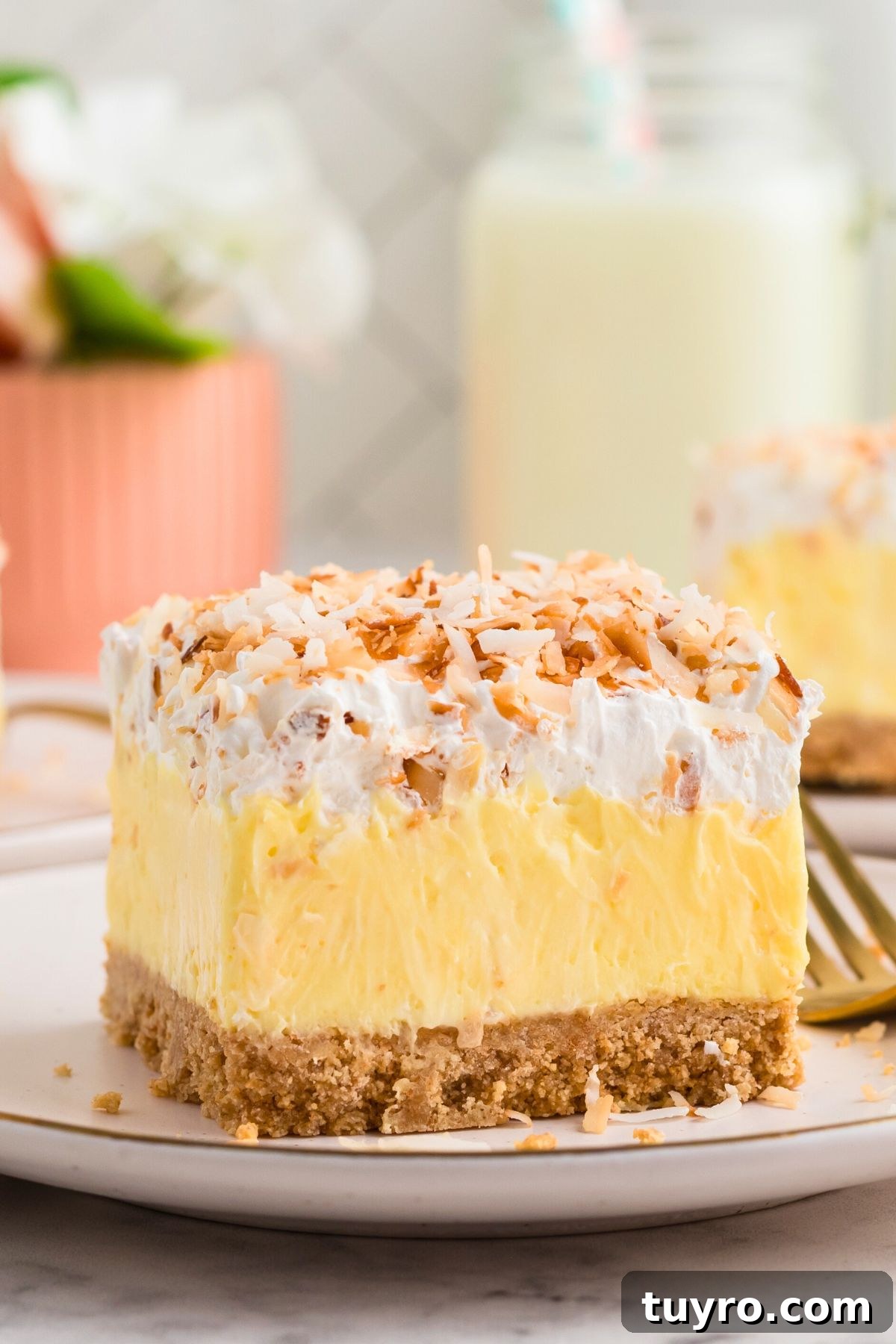 Coconut Delight: Creamy Coconut Dessert Recipe for Home Bakers 2 Graham cracker crusted dessert, topped with cool whip and toasted coconut on a white plate.