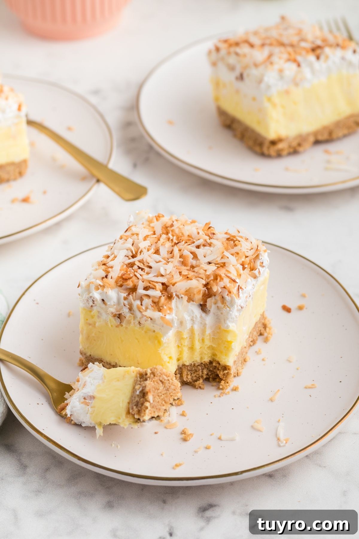 Coconut Delight: Creamy Coconut Dessert Recipe for Home Bakers 9 A slice of coconut delight on a small white plate with a fork on the side.