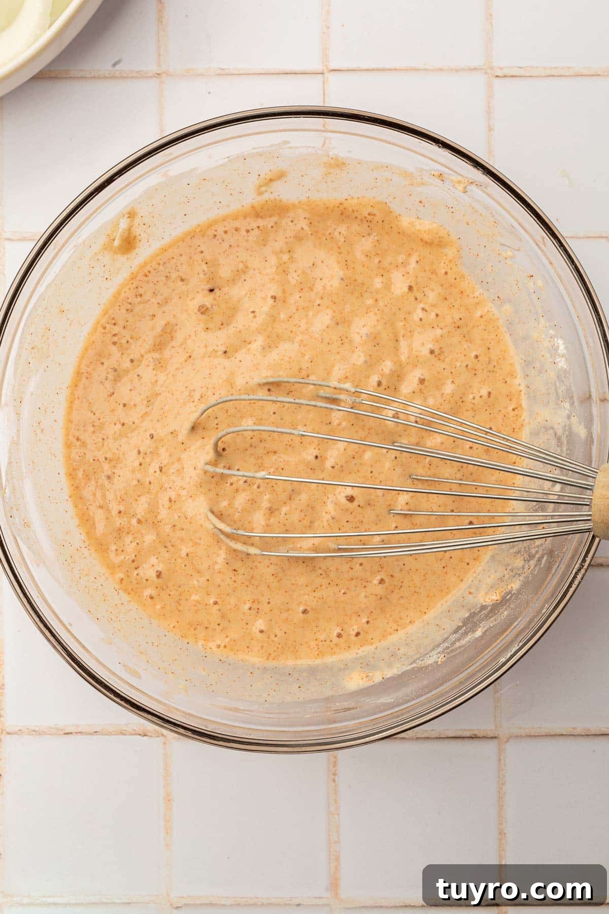 Crispy Gluten-Free Onion Rings Recipe 8 A glass mixing bowl with gluten-free batter and a whisk.