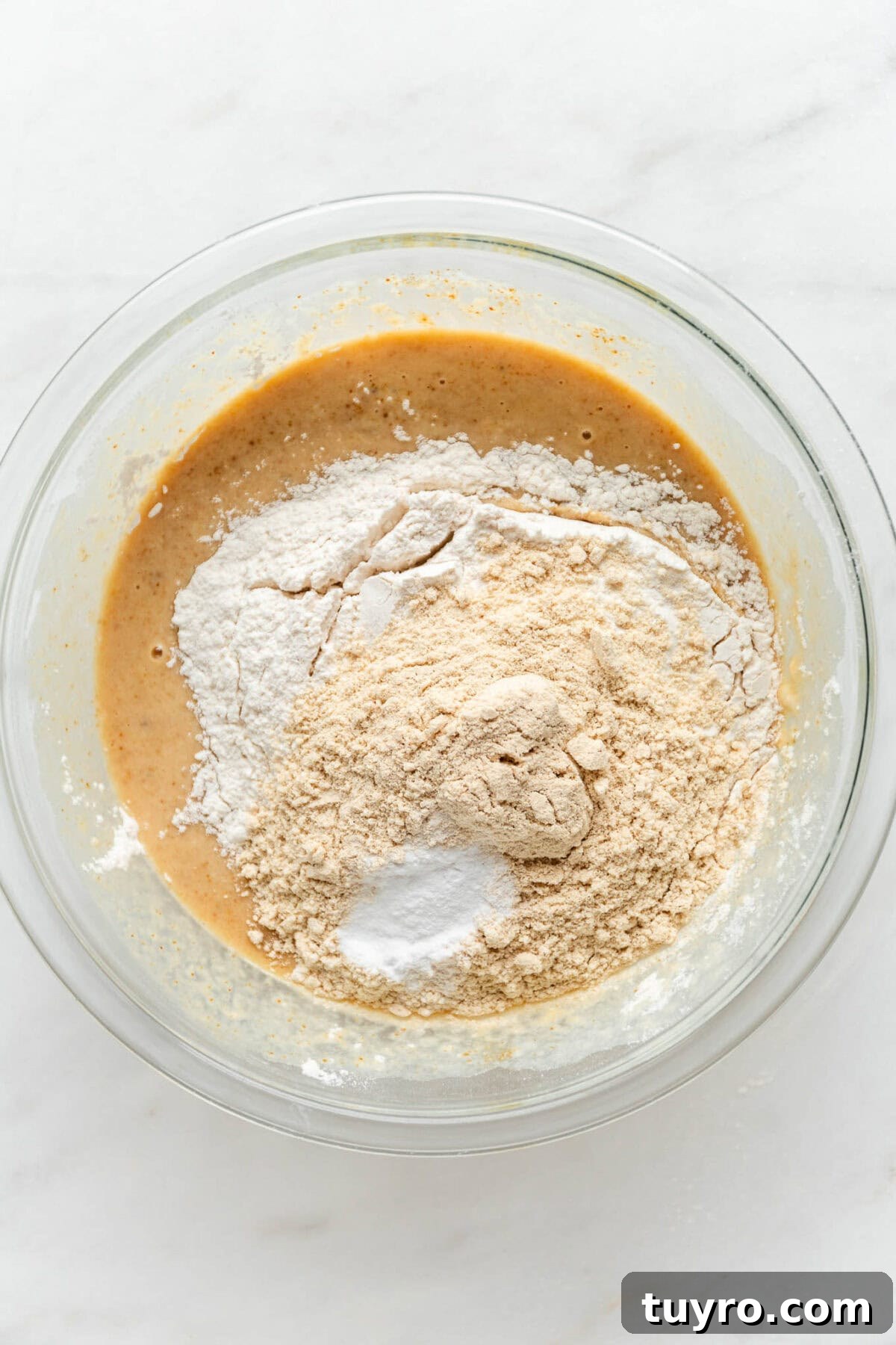High-Protein Banana Muffins for Quick Breakfast and Snacks 6 wet and dry ingredients for banana muffins in a clear bowl.