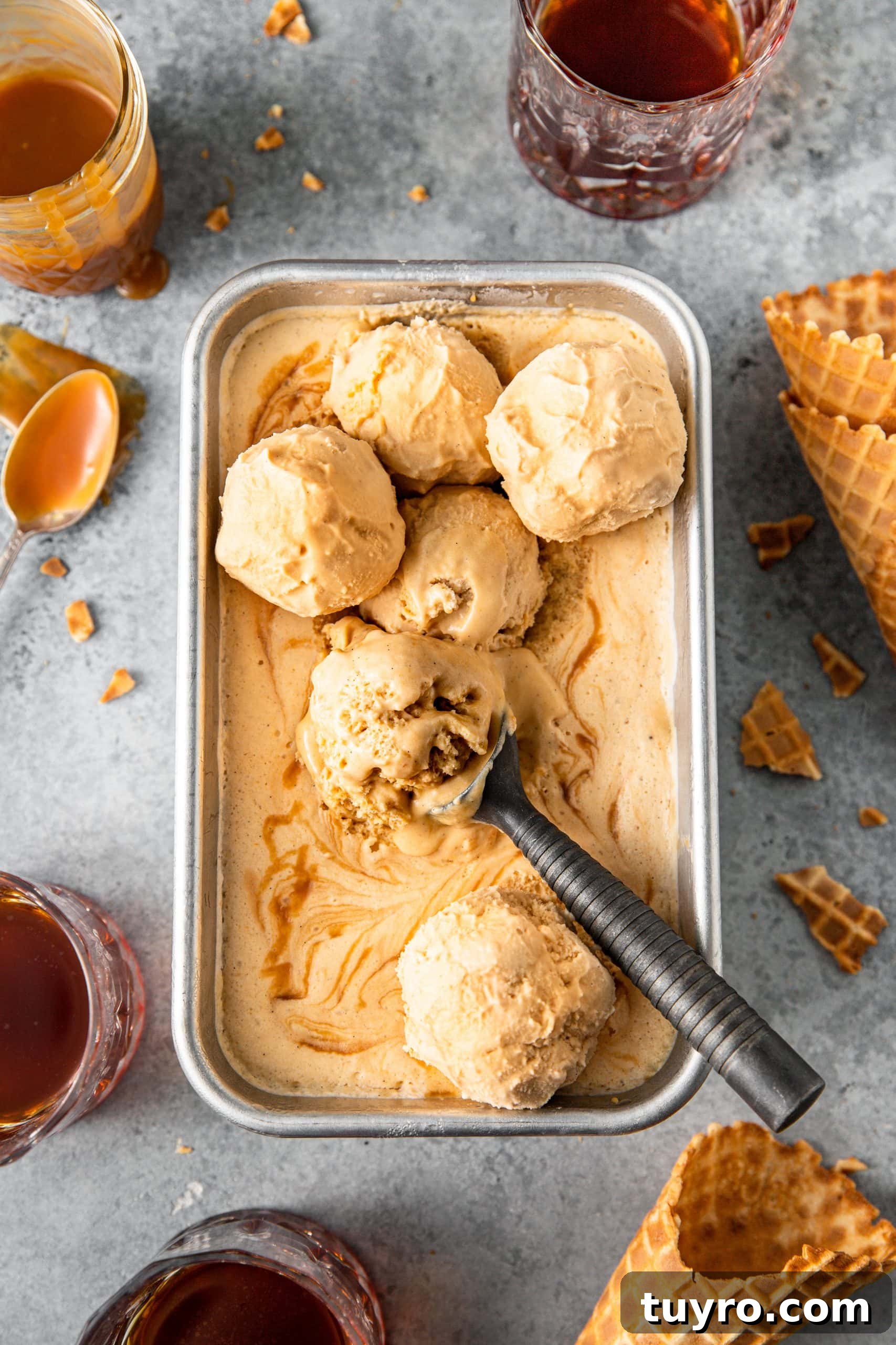 No-Churn Bourbon Salted Caramel Ice Cream Recipe 2 No Churn Bourbon Salted Caramel Ice Cream inside a loaf pan with 6 large scoops showing creamy texture and ice cream cones, bourbon caramel, and a glass of bourbon nearby.