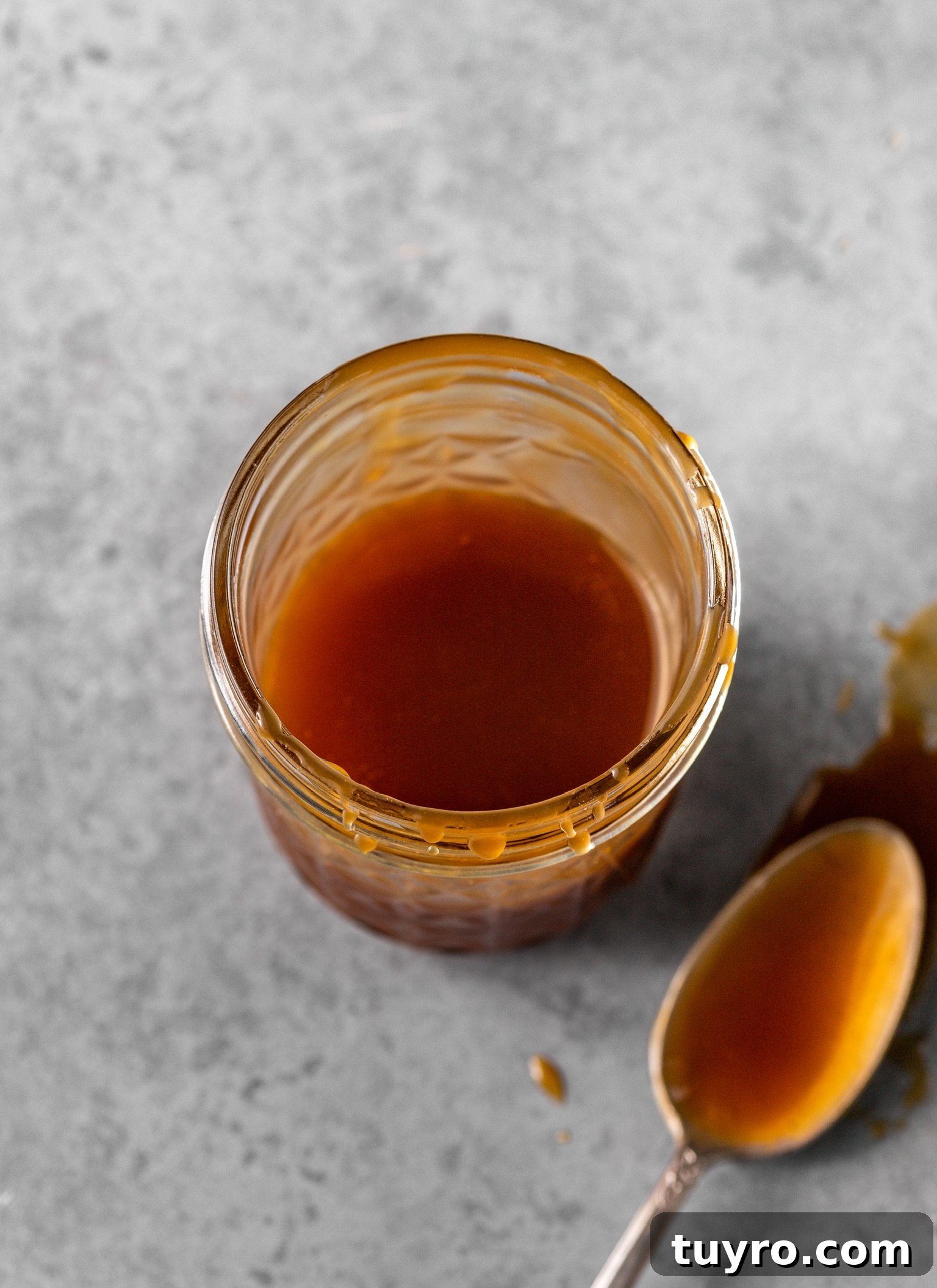 No-Churn Bourbon Salted Caramel Ice Cream Recipe 4 Bourbon salted caramel inside of a mason jar with a caramel-covered spoon nearby