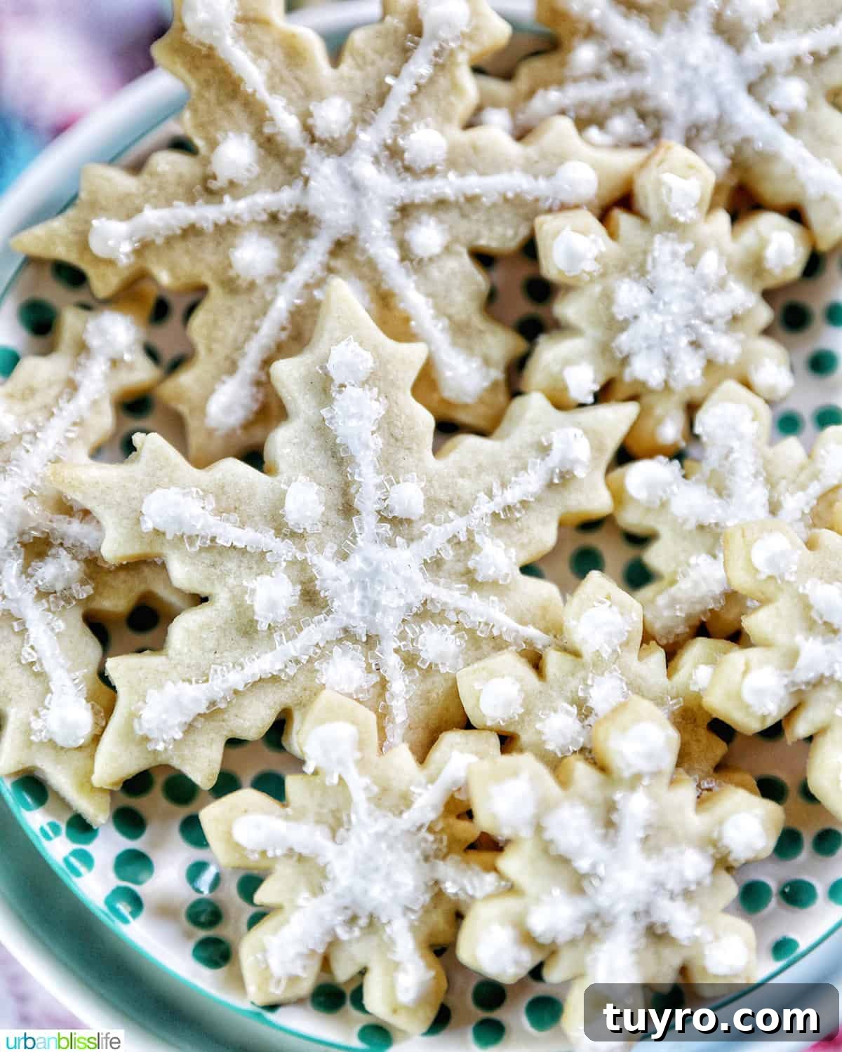 plate full of snowflake sugar cookies decorated with royal icing and decorator sugar.