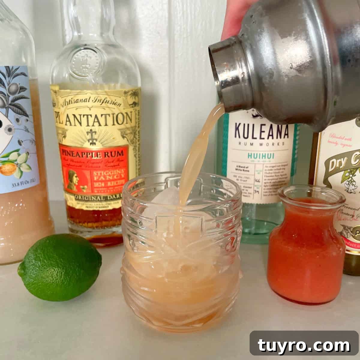 Guava Mai Tai Recipe: Tropical Rum Cocktail with Fresh Guava 5 cocktail shaker pouring a guava mai tai into a tiki glass.