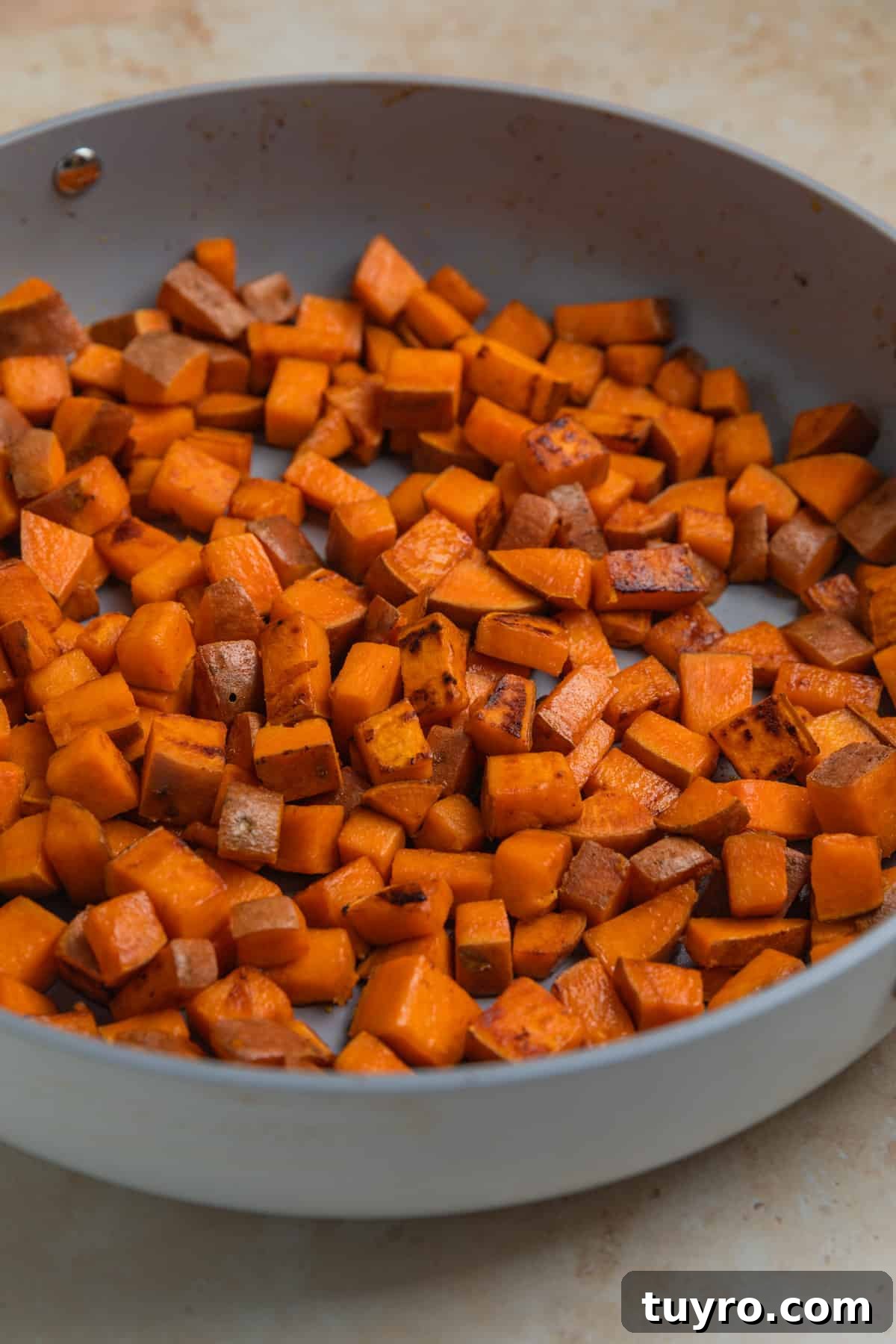 Sweet potatoes cooked in an even layer in skillet.
