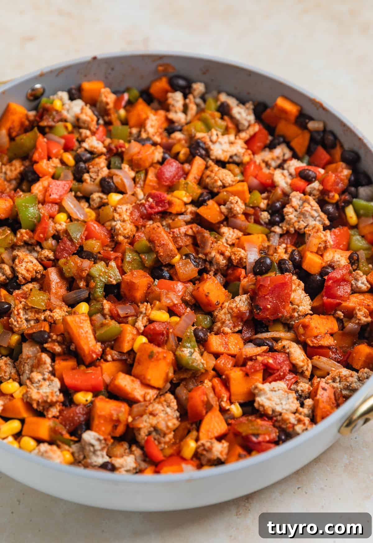 Turkey and pepper mixture stirred into sweet potato, bean, corn mixture in skillet.