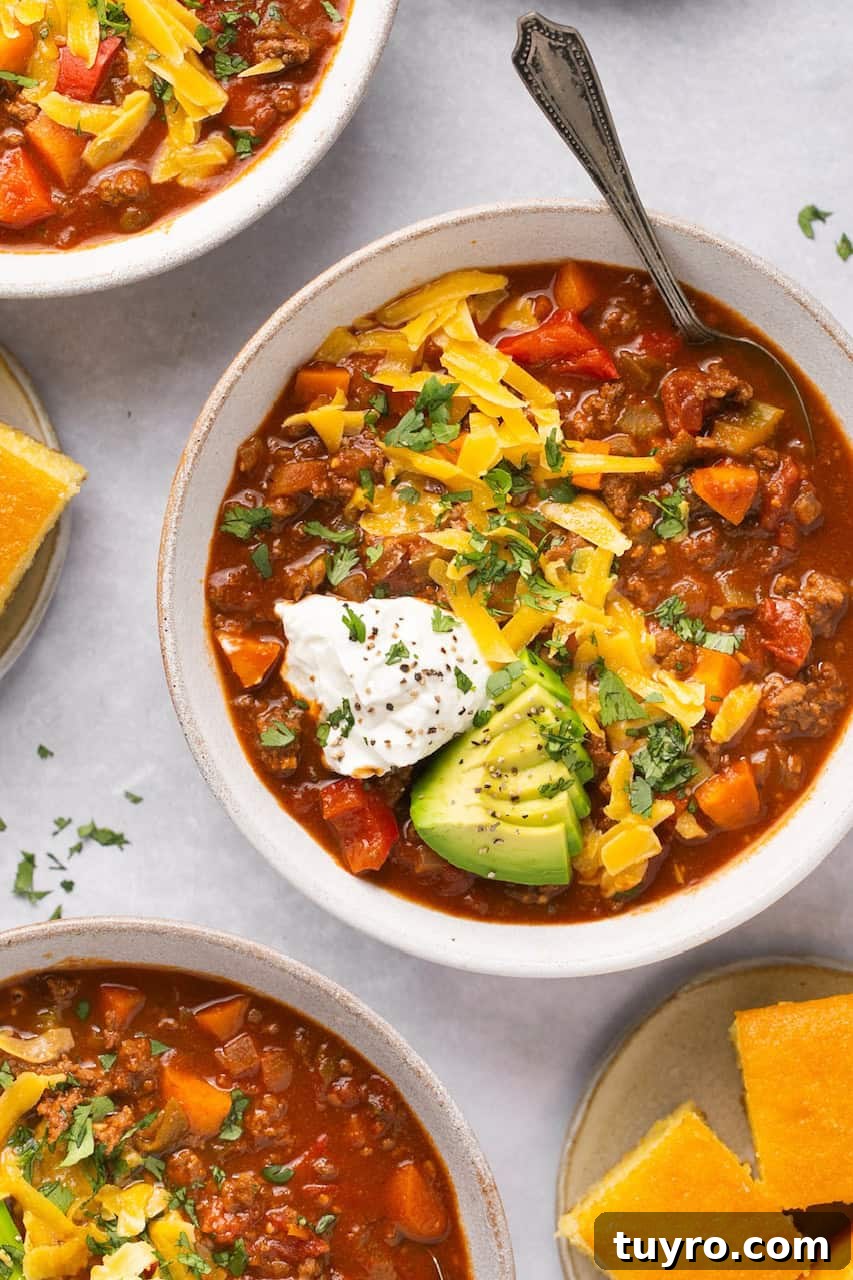 Hearty No-Bean Chili Recipe for Rich, Meaty Flavor 5 3 bowls of chili with toppings and cornbread on the side