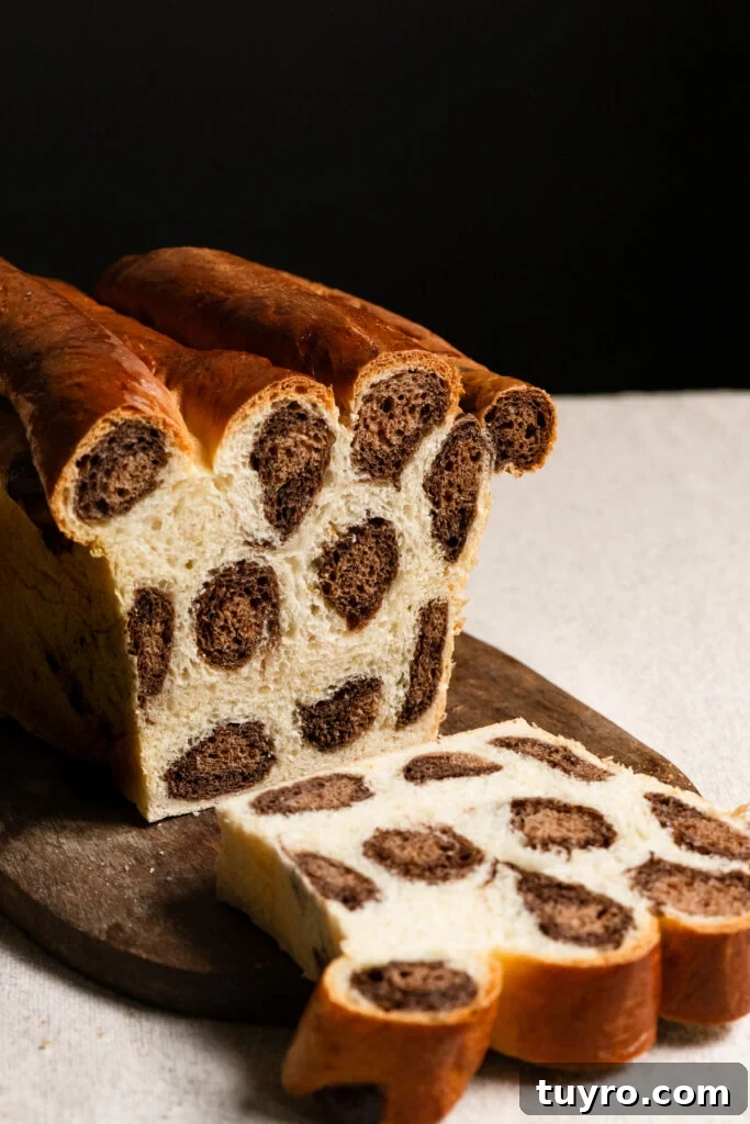 Leopard Milk Bread Recipe: Marbled Hokkaido-Style Loaf 3 Loaf of leopard bread on a cutting board with a slice cut.