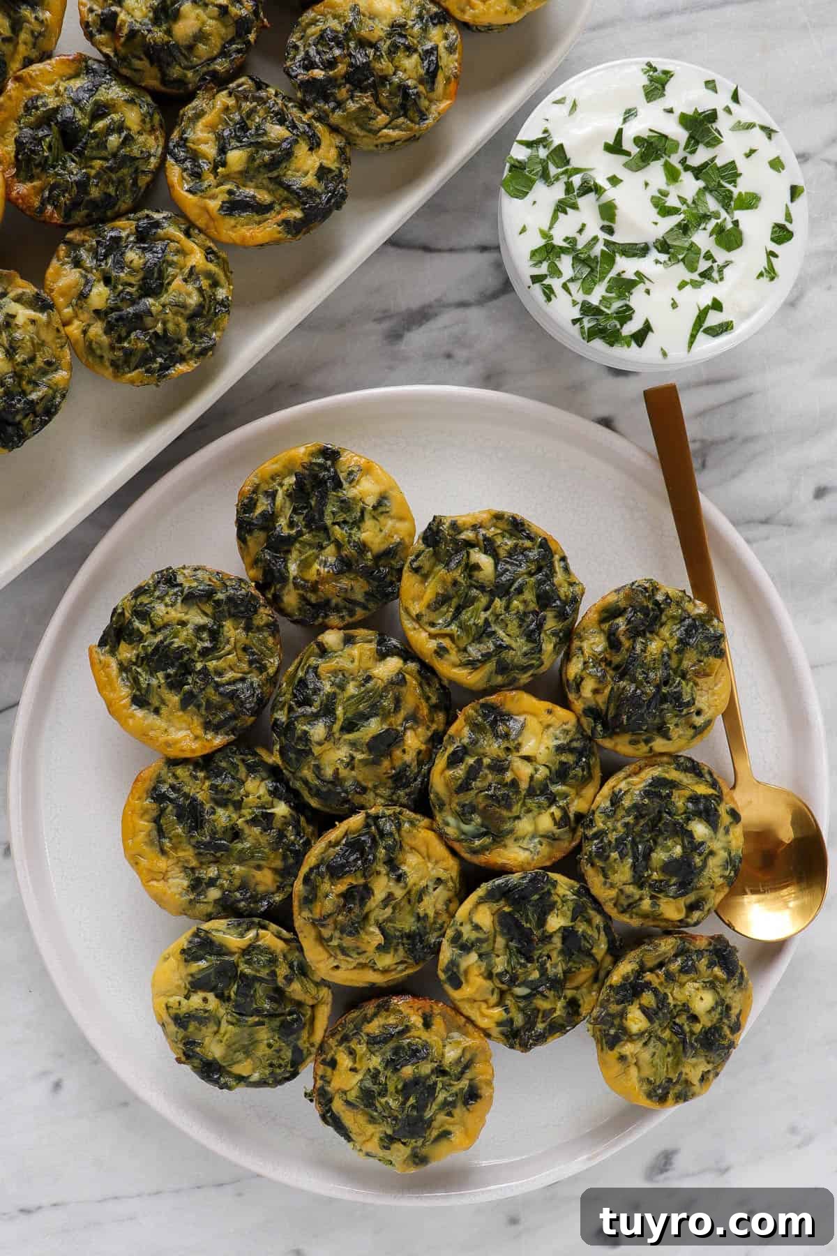 Mini spinach and feta quiche on plate and platter with yoghurt topping sauce.