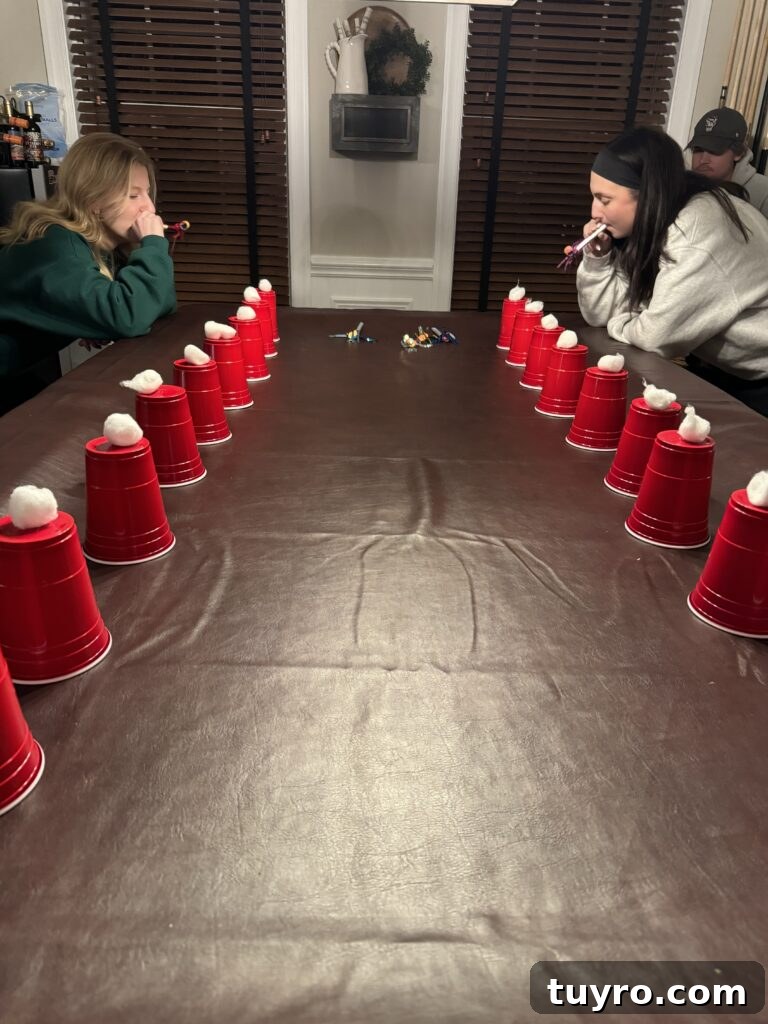 30+ Activities to Connect with Your Young Adult Children 3 Two young women competing in a Christmas game by blowing cotton balls off red cups with party blowers.