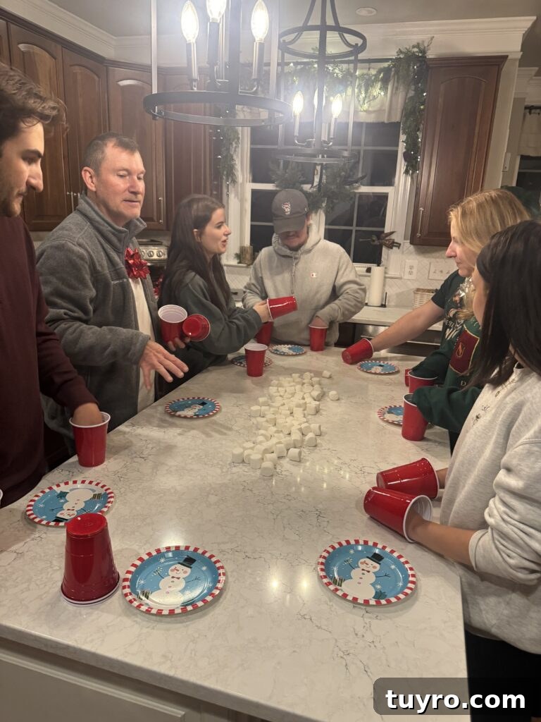 30+ Activities to Connect with Your Young Adult Children 5 Family gathered around the kitchen island playing a fun holiday cup and marshmallow game on Christmas game night.