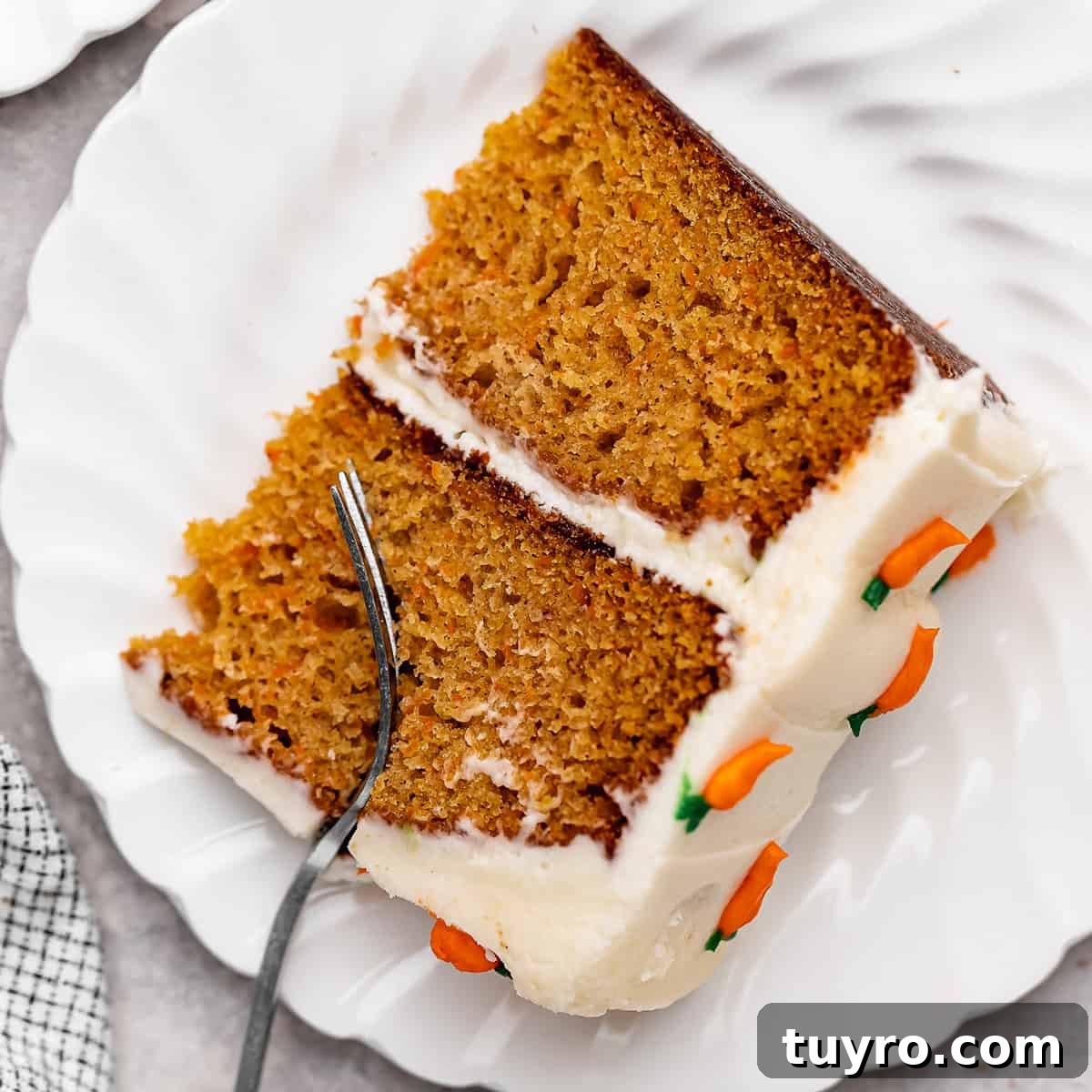 Moist Carrot Cake Recipe with Cream Cheese Frosting 5 a fork taking a bite out of a slice of Carrot Cake