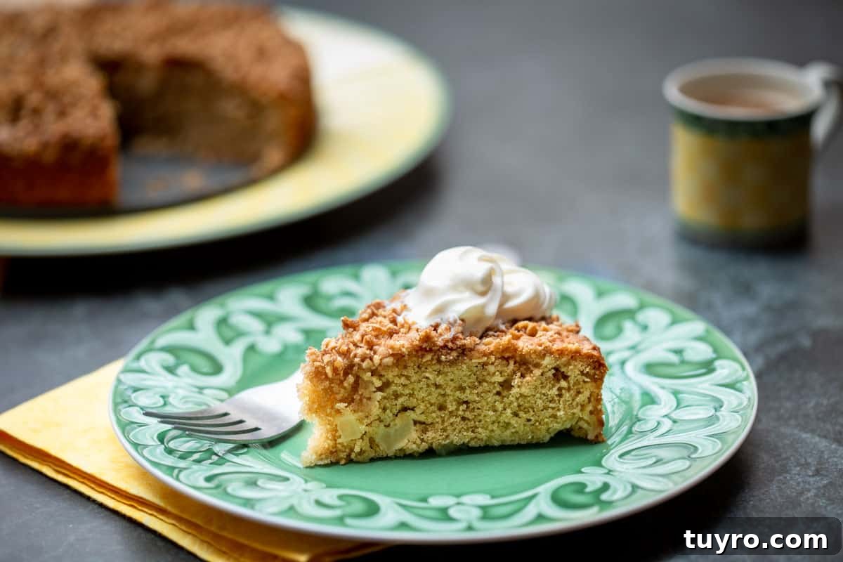 Moist Apple Almond Cake Recipe with Cinnamon 10 plate with slice of almond apple cake with cake platter and cup of coffee in background
