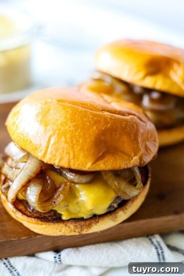two smash burgers on a wooden platter with american cheese and sautéed onions