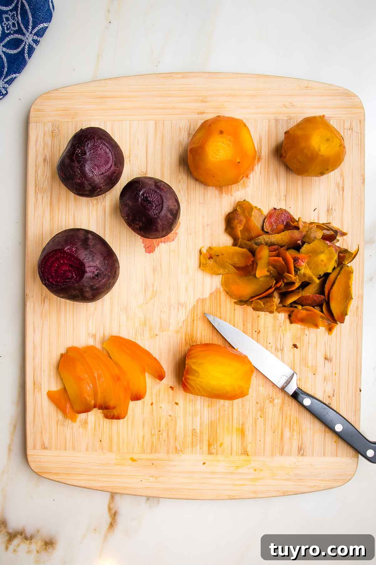 Roasted Beet Salad with Balsamic Vinaigrette and Goat Cheese 12 Roasted whole golden beets and red beets, peeled and now being cut into wedges with a paring knife, on a wooden cutting board to make into beet salad.
