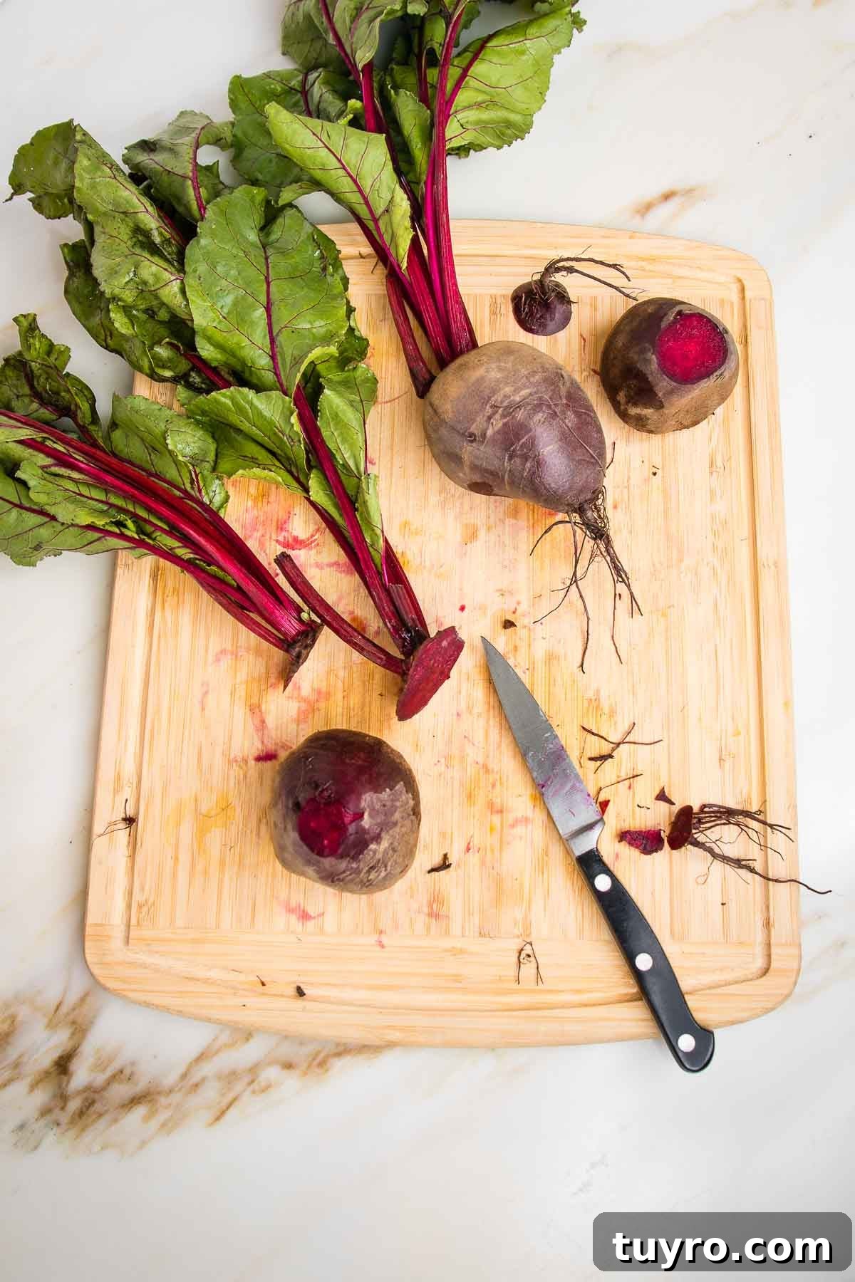 Roasted Beet Salad with Balsamic Vinaigrette and Goat Cheese 5 Trimming beet roots on a wooden board with a paring knife.