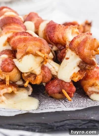 Bacon wrapped mozzarella sticks after being fried on a serving board.